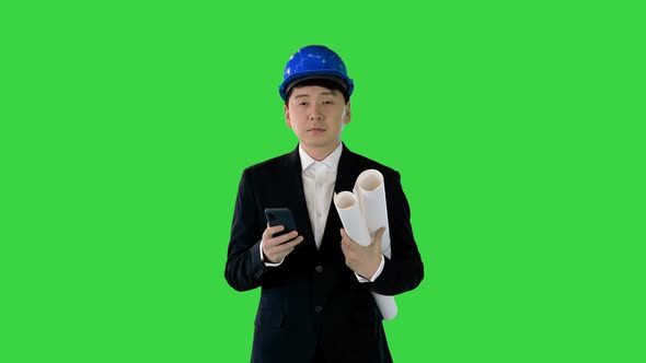 Architect Man Holding Blueprints Using Smartphone and Walking on a Green Screen Chroma Key