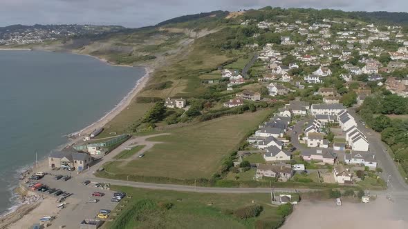 Aerial of Charmouth, Dorset. On a sunny day. Tracking back and curving around to reveal more of the