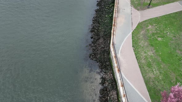 A top down view of the East River near a park in Queens, NY on a cloudy day. In view is the edge of
