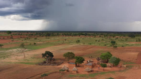 A traditional African village with heavy storm clouds rolling in rural Zambia, Africa. 4K