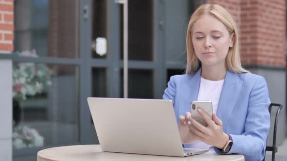 Young Businesswoman Using Smartphone and Laptop Sitting Outdoor