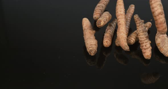 Turmeric, curcuma longa, Roots falling against Black Background, Indian Spice, Slow Motion 4K