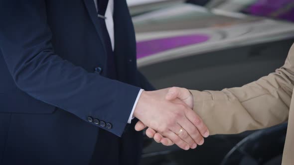 An Unrecognizable Manager Shakes Hands with a Client and Hands Over the Car Key