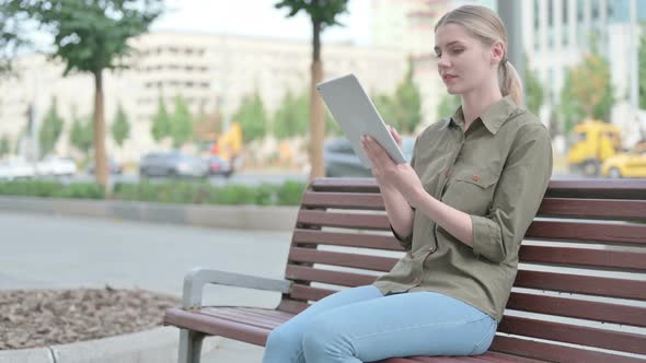 Woman using Tablet while Sitting Outdoor on Bench