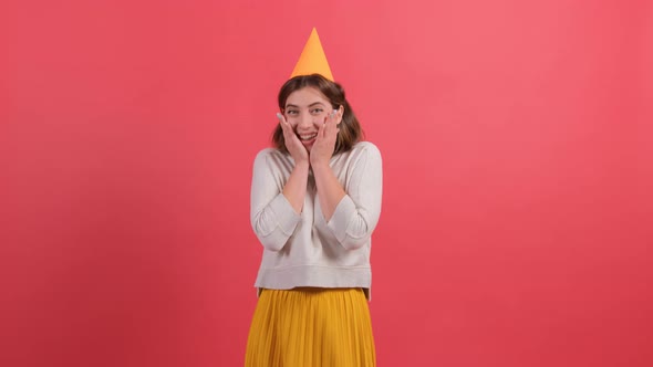 Excited Young Woman in Birthday Hat Posing Isolated on Red Background