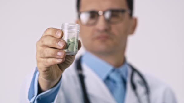 Handsome Doctor Pouring Down Green Pills From Transparent Jar, Close Up