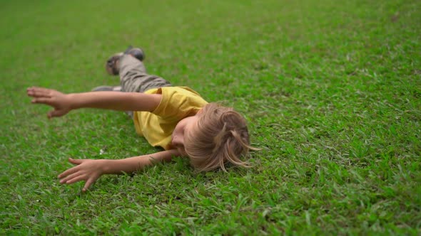 Superslowmotion Shot of Two Little Boys Have Fun on a Lawn. They Roll Down the Hill