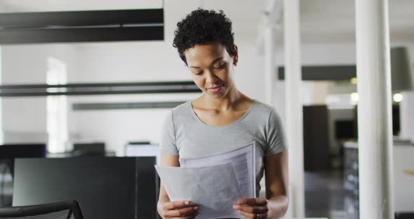 Focused biracial businesswoman checking documents in office