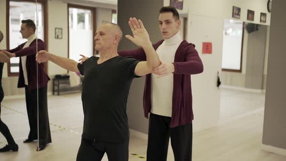 Man dancing with help of instructor during ballroom dance class