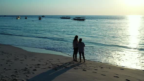 Ladies together happy and smiling on marine seashore beach holiday by shallow water and white sand b