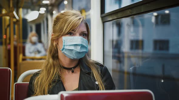 Girl Hipster in Protective Mask is Riding a Tram Sitting on Seat and Looking Out the Window