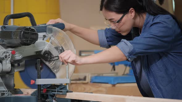 Young woman use electric cutter to cut wood