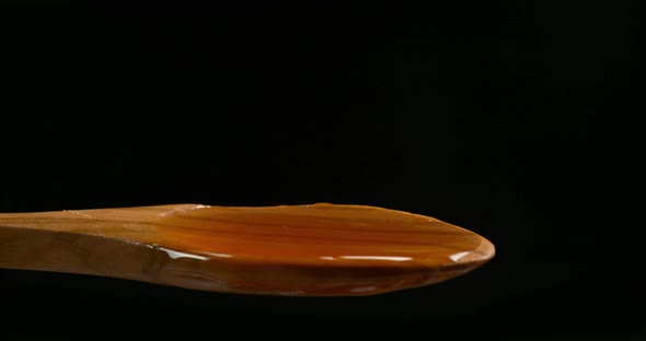 Almond falling in a spoon of Honey on Black Background, Slow Motion 4K