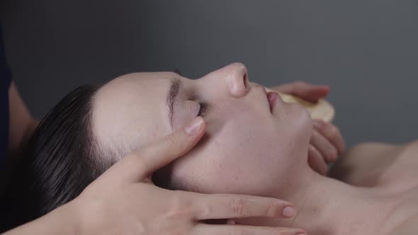 Woman Massagist Using a Wooden Tool Under the Jaw of Her Female Client