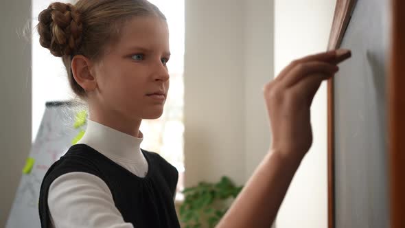 Smart Teen Girl Solving Math Problem Standing at Chalkboard Thinking alt