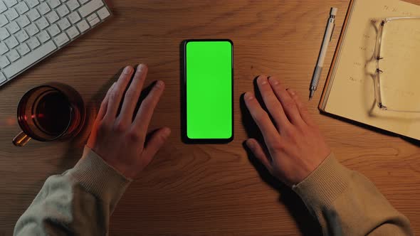 Man Using Mobile with Green Mockup Screen at Workplace