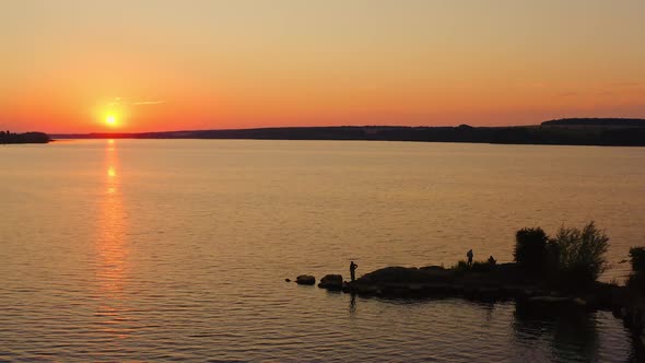 Beautiful sunset over the river. People fishing in the evening.