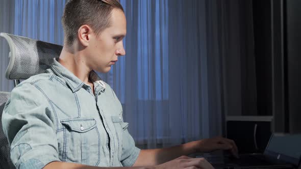 Sliding Shot of a Male Freelancer Working Late in the Evening Using Two Computers