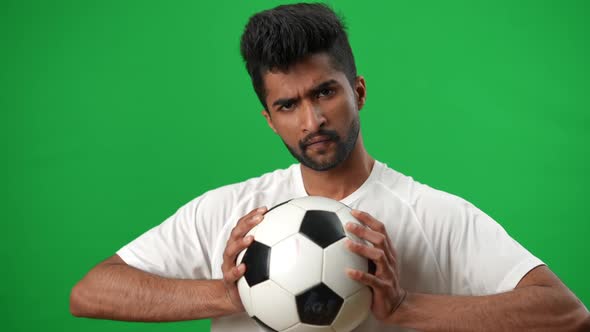 Serious Focused Middle Eastern Sportsman Looking at Camera Holding Soccer Ball on Green Screen