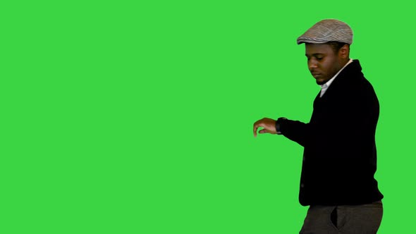 African American Businessman in a Hat Walking and Looking at His Wristwatch on a Green Screen Chroma
