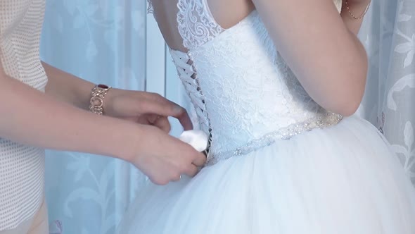 Bride's Bride Helps the Bride Wear a Wedding Dress Closeup