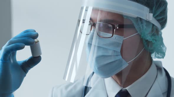 Studio portrait of young professional medical doctor in mask, hat and protective visor.