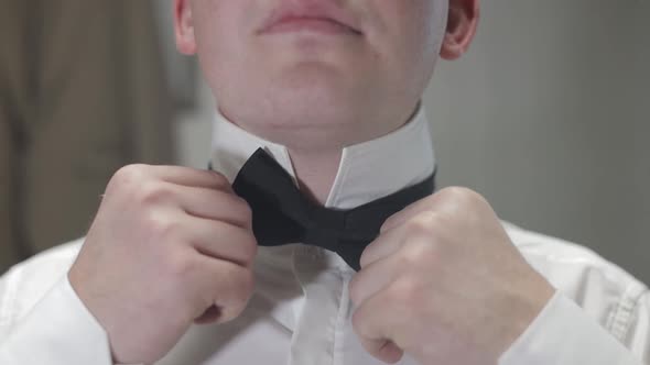 Groom Adjusts Bow Tie. Preparing To Go To the Bride. Businessman in White Shirt. Wedding Day