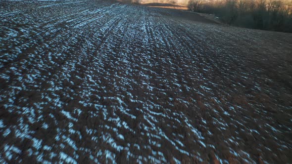 AERIAL: Rows of Plowed Earth Covered with Snow and Frost in Early Spring