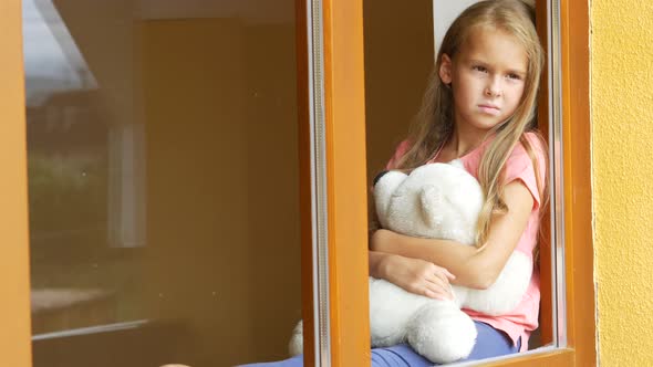 Beautiful Young Girl With Soft Toy Looking Through the Window