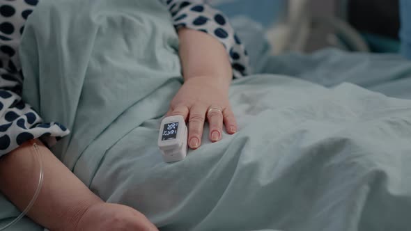 Close Up of Oximeter on Hand of Senior Patient in Bed