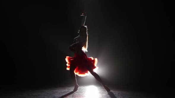 Professional Dancer in Beautiful Dress in the Studio on a Dark Background, with White Backlight, a