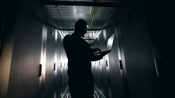 Backlit Computer Engineer Is Working in the Server Room