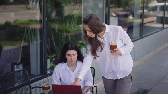 Two Confident Young Women Discussing Startup Project on Cafe Summer Terrace with Drinks