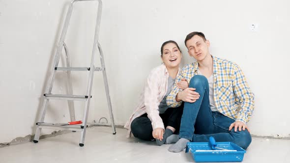 Young Woman and Guy Wave and Talk Sitting Near Empty Wall