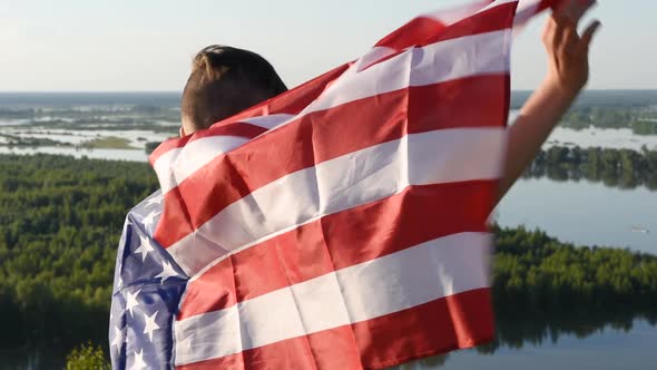 Boy Waving National USA Flag Outdoors Over Blue Sky at the River Bank