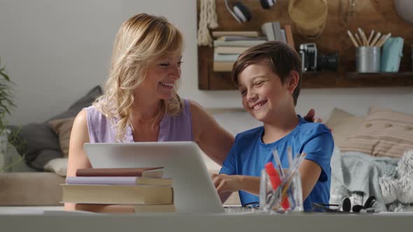 Happy family at home, mother and son have fun using computer