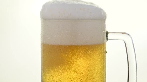 Pouring fresh lager beer in big glass mug over white background