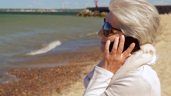 Senior Woman Calling on Smartphone on Summer Beach