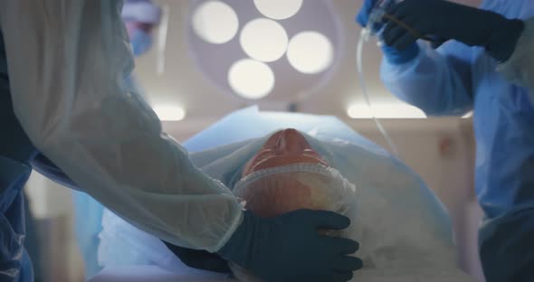 Cropped Shot of Anesthetist at Operating Room Putting Oxygen Mask on Patient Face