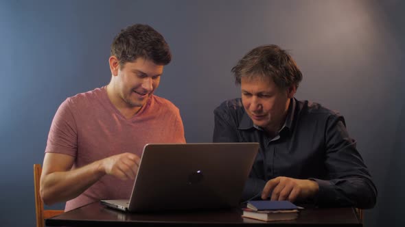 Man Talks with Senior Father Teaching Use Computer at Table