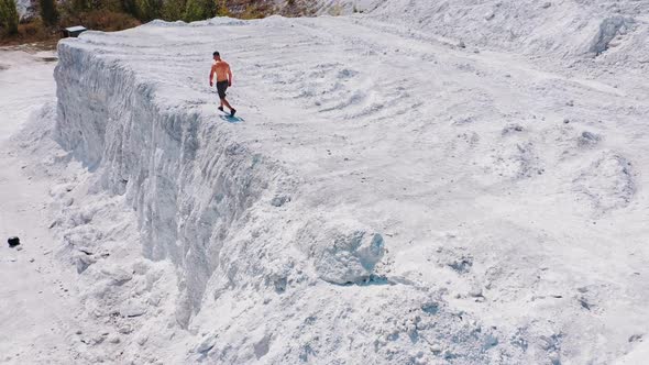 Bodybuilder in the mountains. Athletic man walking along the white rocky canyon.