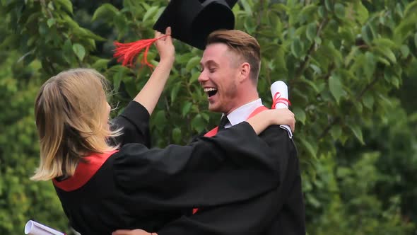 Couple in Love Hugging and Turning Around, Happy Graduates Having Fun in Park