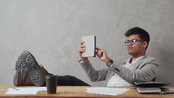 Positive Indian businessman leafing tape on tablet