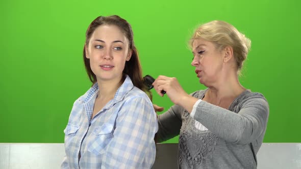 Woman Is Combing Her Daughter. Green Screen