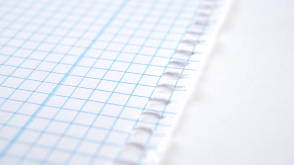 Torn white school sheet of notepad crumpled paper. Checkered blue pattern