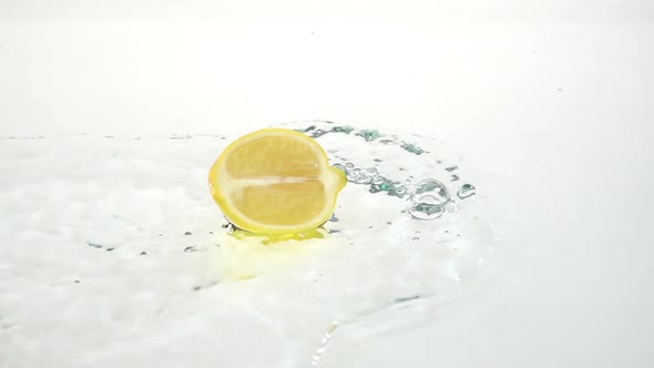 Half a Lemon Drops Into the Water. White Background. Slow Motion