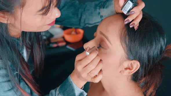 Close up of professional make up artist putting the eyeliner on the woman's eyes