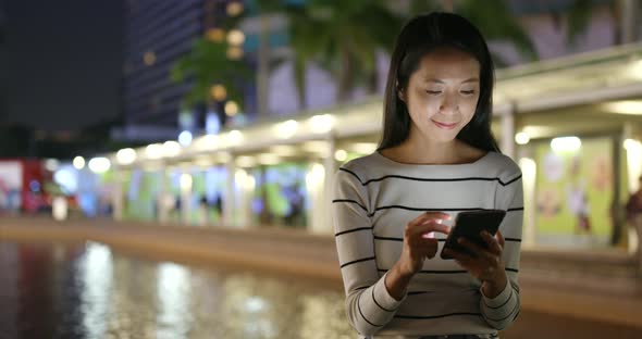 Woman looking at mobile phone in city at night