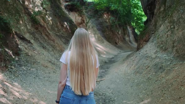 Back View of Pretty Blonde Woman Walking in Natural Loess Ravine