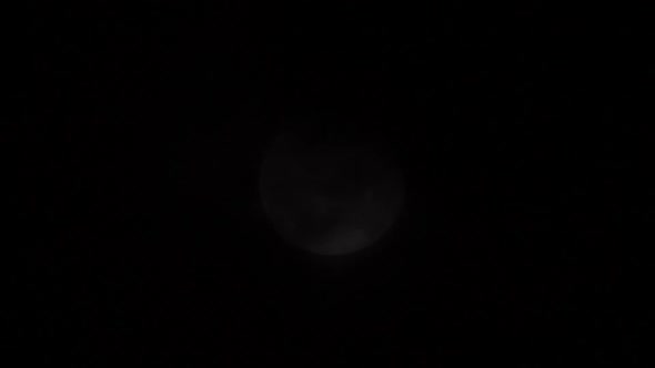 Dark Clouds Passing In Front Of The Moon In The Sky At Dusk alt
